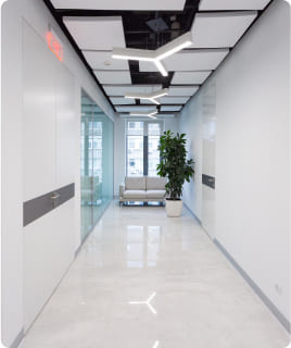 Moderne Büroflur mit stilvoller Beleuchtung und Pflanzen, ideal für effizientes Arbeiten.