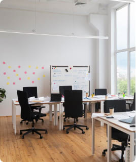 Moderne Büroeinrichtung in hellem Raum mit großen Fenstern und Konferenztisch.